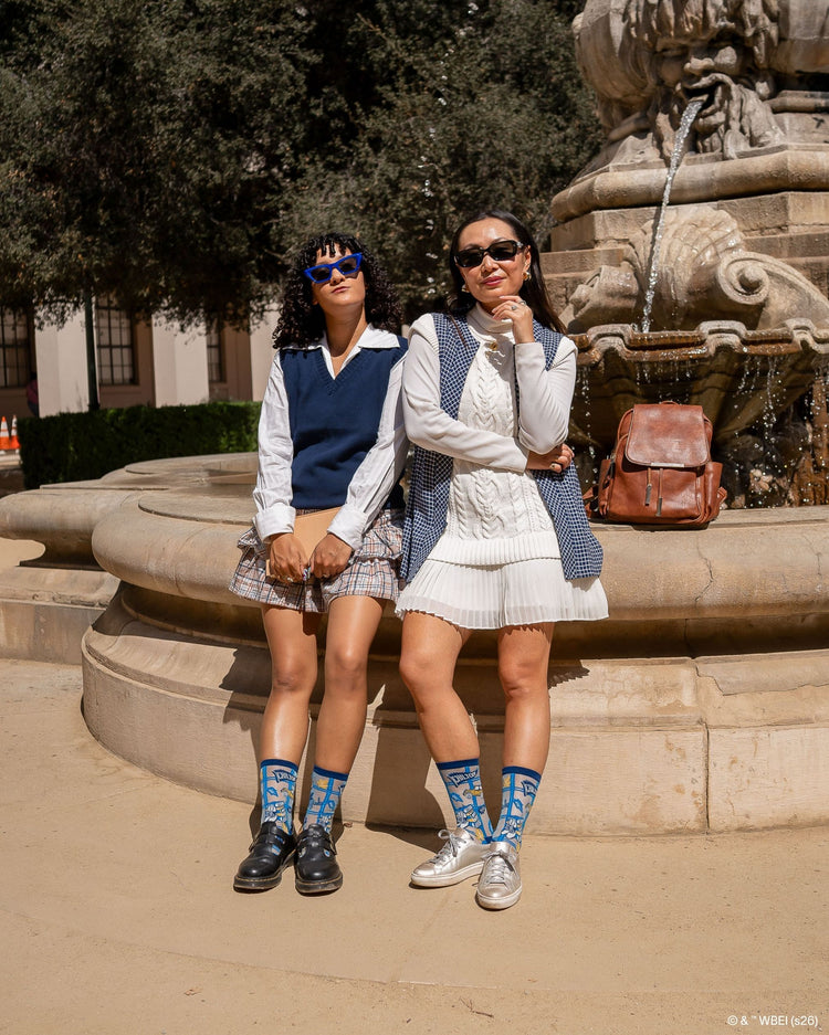 Two women wearing Sock Candy Gilmore Girls Chilton plaid sheer crew socks in an academic uniform aesthetic, styled with black leather Doc Martens and silver sneakers.