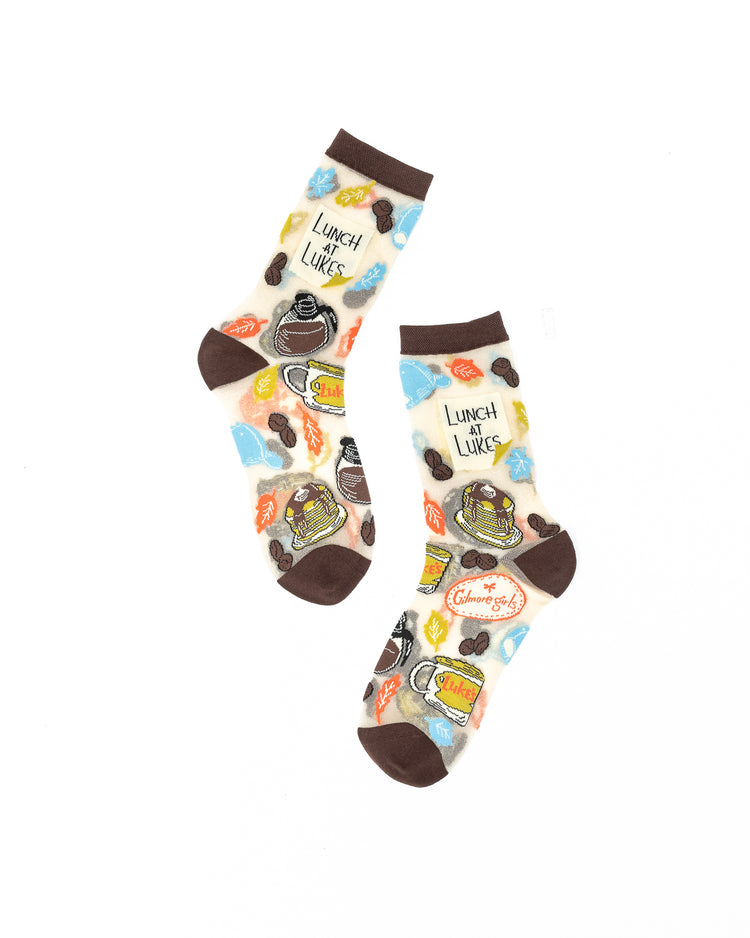 Sock Candy Gilmore Girls Luke's Diner brown sheer crew socks decorated with coffee pots and autumn leaves on a white background.
